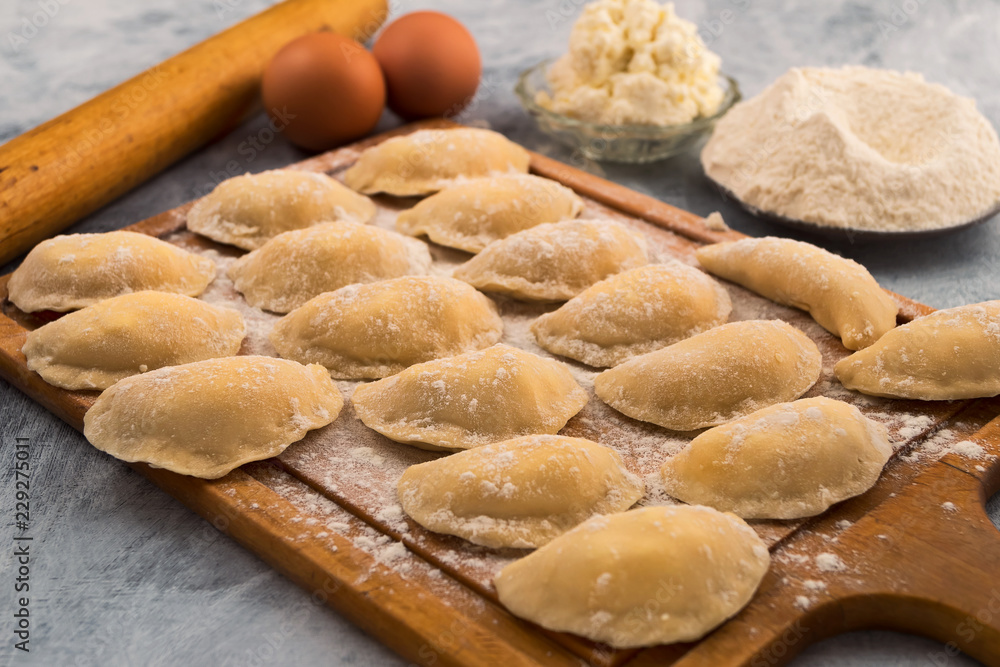Raw dumplings stuffed on a cutting Board, flour, cottage cheese, eggs. Raw dumplings stuffed on a cutting Board, flour, cottage cheese, eggs.