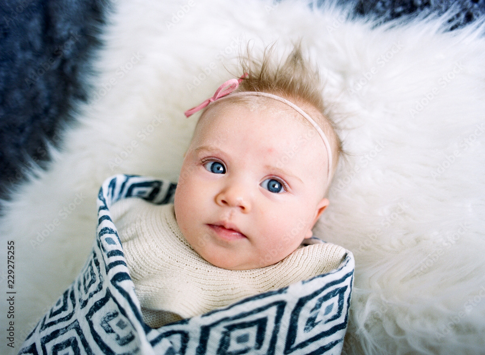 overhead view of blue eyed baby on white fur blanket overhead view of blue eyed baby on white fur blanket