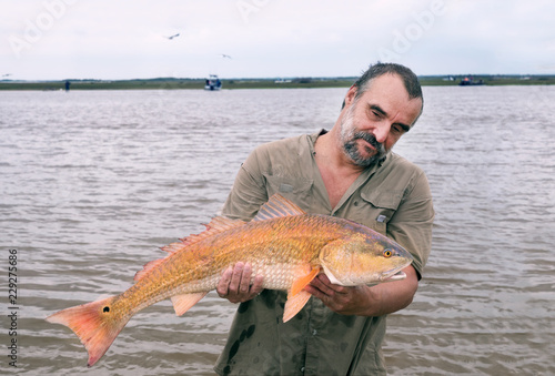 Fisherman with a big catch - golden fish Red drum (Sciaenops ocellatus). Texas Gulf Coast, USA