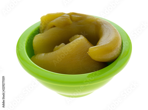 Side view of two canned green chiles in a small bowl isolated on a white background.