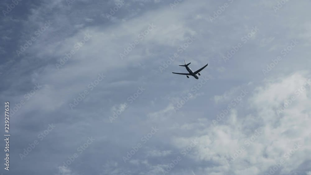 From below view of plane flying high in blue sky with slight clouds From below view of plane flying high in blue sky with slight clouds