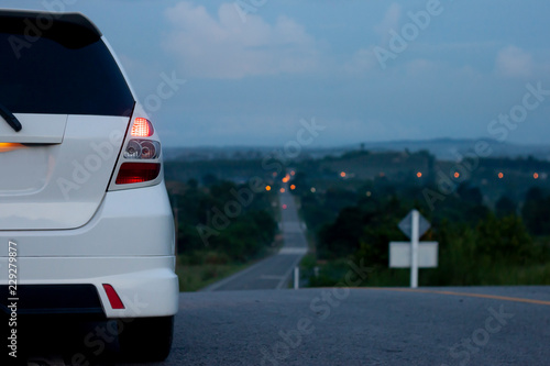 Hatchback car white color stop ton the road on morning trip travel to Country at Rayong Thailand.