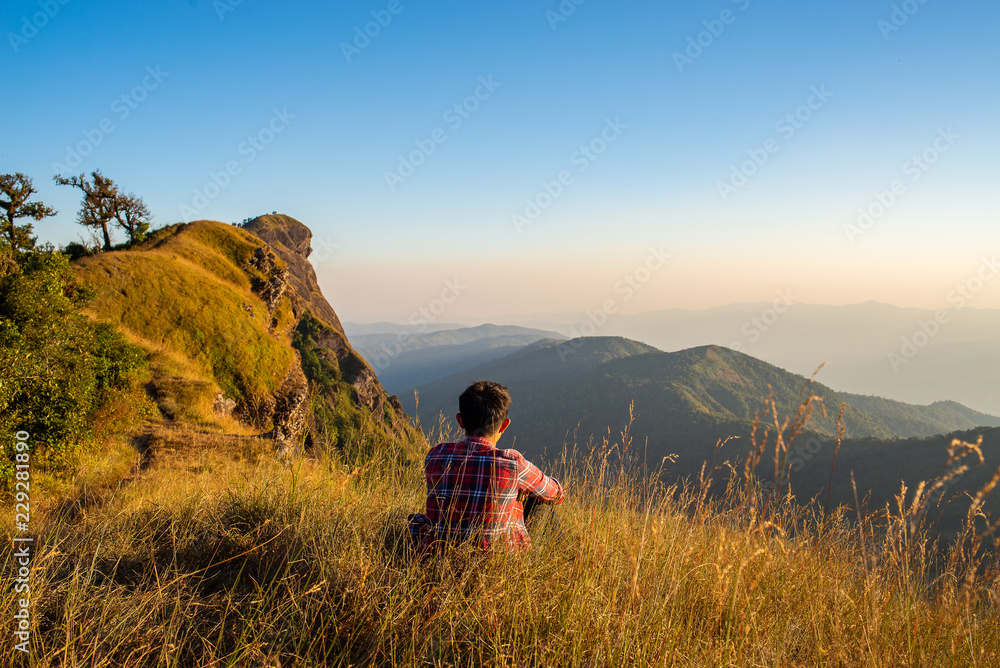 Young traveler hiker on top of mountain and looking view of gold field.