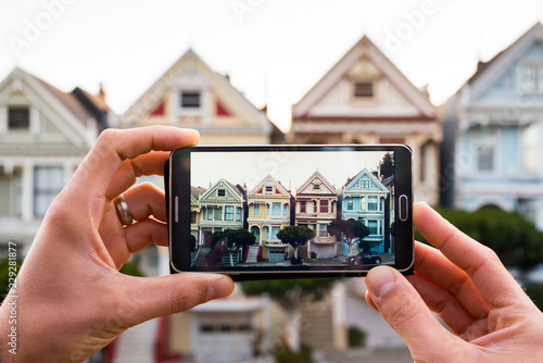 Man uses smartphone to photograph homes on a San Francisco hill
