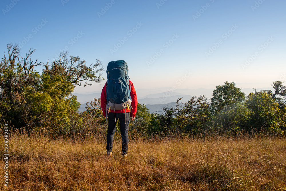 Young traveler with backpack enjoying with beautiful view on top of mountain.