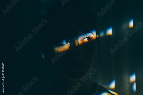 Teenage girl In the dark with a slice of light in her eyes