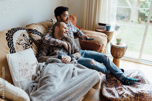 Young Gay couple Realxing on the Couch of the Living Room Watchi photo