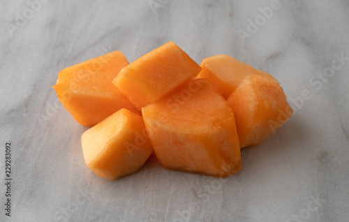 Side view of a serving of cantaloupe chunks on a marble counter top.