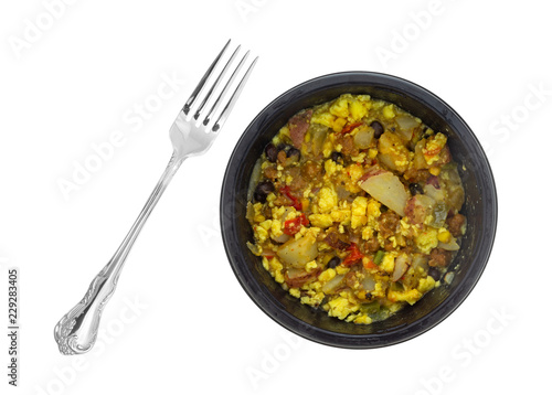 Top view of a microwaved scrambled egg burrito meal in a black tray with a fork to the side isolated on a white background.