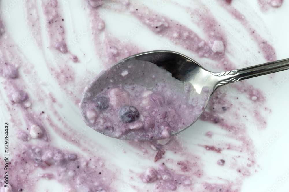 Overhead view of a finished meal of blueberries and cottage cheese on a white plate with a spoon. Overhead view of a finished meal of blueberries and cottage cheese on a white plate with a spoon.