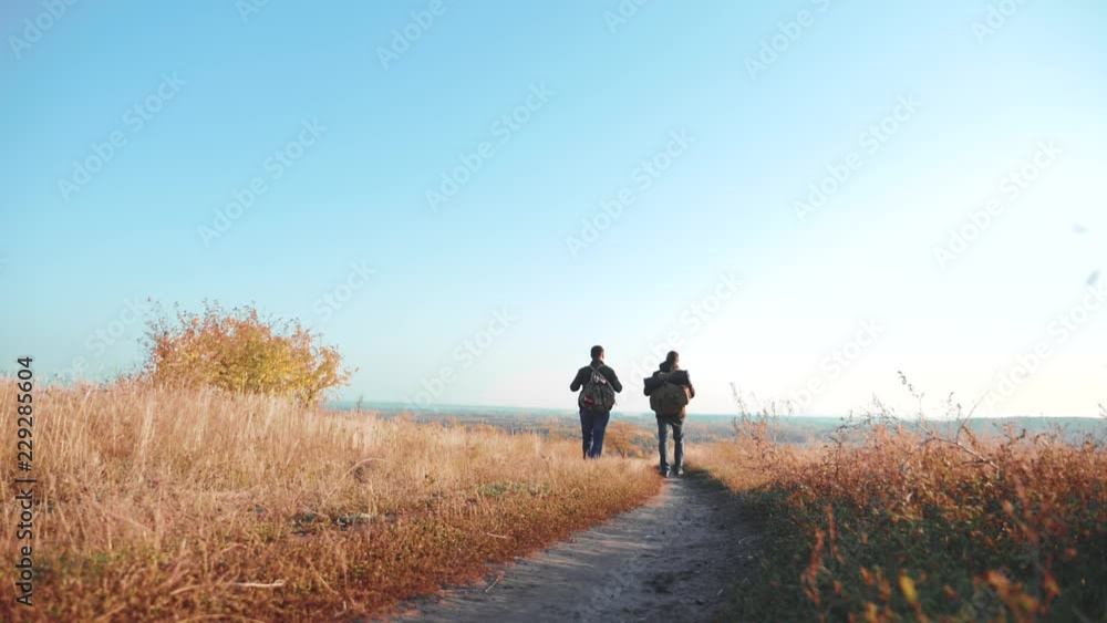 Two men traveler hiking with backpacks are walking along the path climbing into the mountains. slow motion video. Tourist Hipster Hiker traveler on background view blue sky clouds go hiking trip Two men traveler hiking with backpacks are walking along the path climbing into the mountains. slow motion video. Tourist Hipster Hiker traveler on background view blue sky clouds go hiking trip