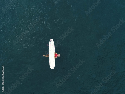 Top view: girl relaxing with surfboard at waves photo