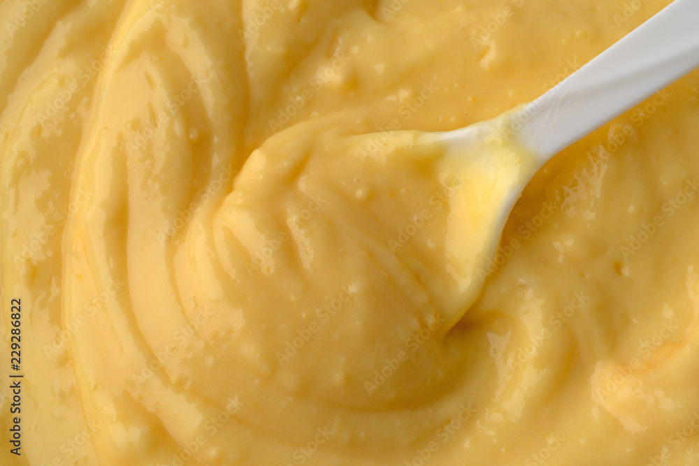 Top close view of fresh creamy homemade banana cream pudding with a white plastic spoon in the food illuminated with window light. Top close view of fresh creamy homemade banana cream pudding with a white plastic spoon in the food illuminated with window light.