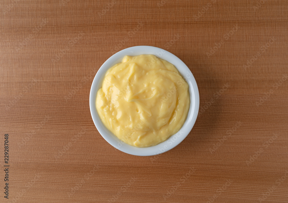 Top view of homemade banana cream pudding in a white dish atop a wood table illuminated with window light. Top view of homemade banana cream pudding in a white dish atop a wood table illuminated with window light.