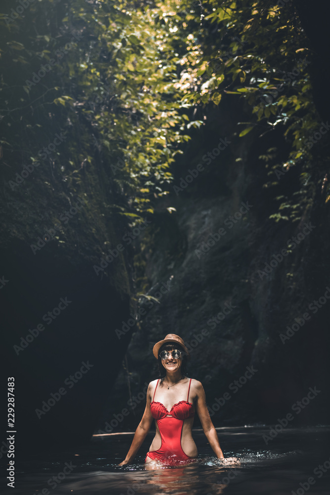 Fototapeta premium Young traveler woman in the jungle river. Rainforest of Bali island. Tourist adventure concept.