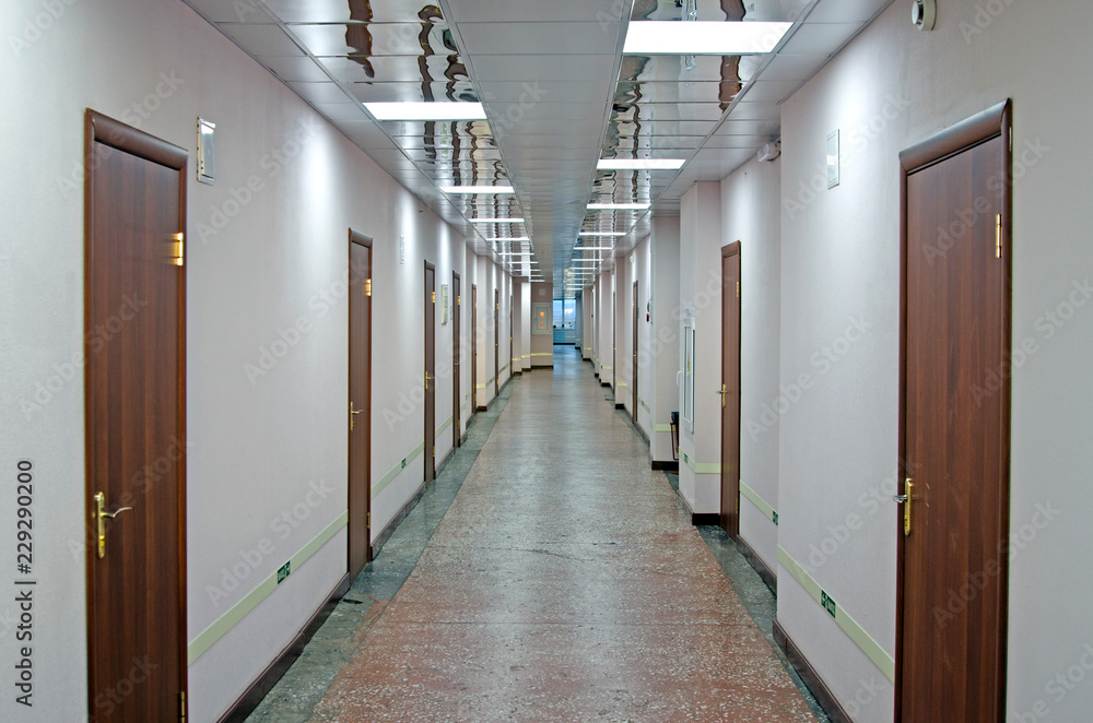 A long corridor with doors to offices. Marble floors, mirrored ceiling.