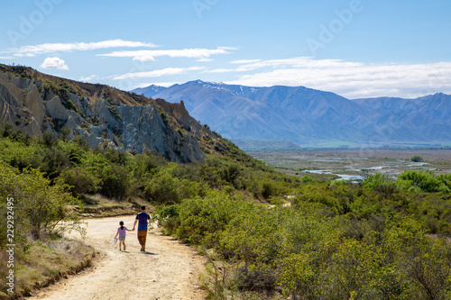 A father and daughter returning along a track to the Clay Cliffs overlooking the river valley at Omarama, New Zealand