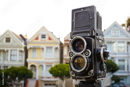 Twin-lens reflex camera on a tripod in front of a row of homes photo