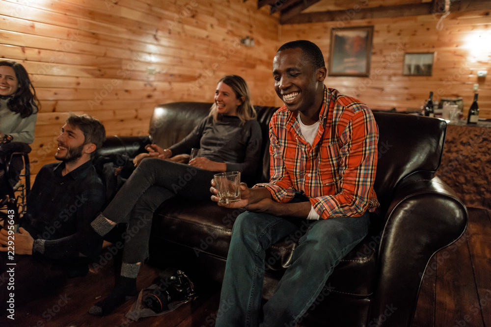 A young man laughs with friends in a cabin in upstate New York A young man laughs with friends in a cabin in upstate New York