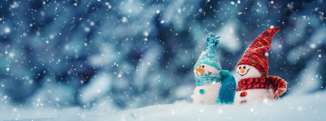 little knitted snowmans on soft snow on blue background