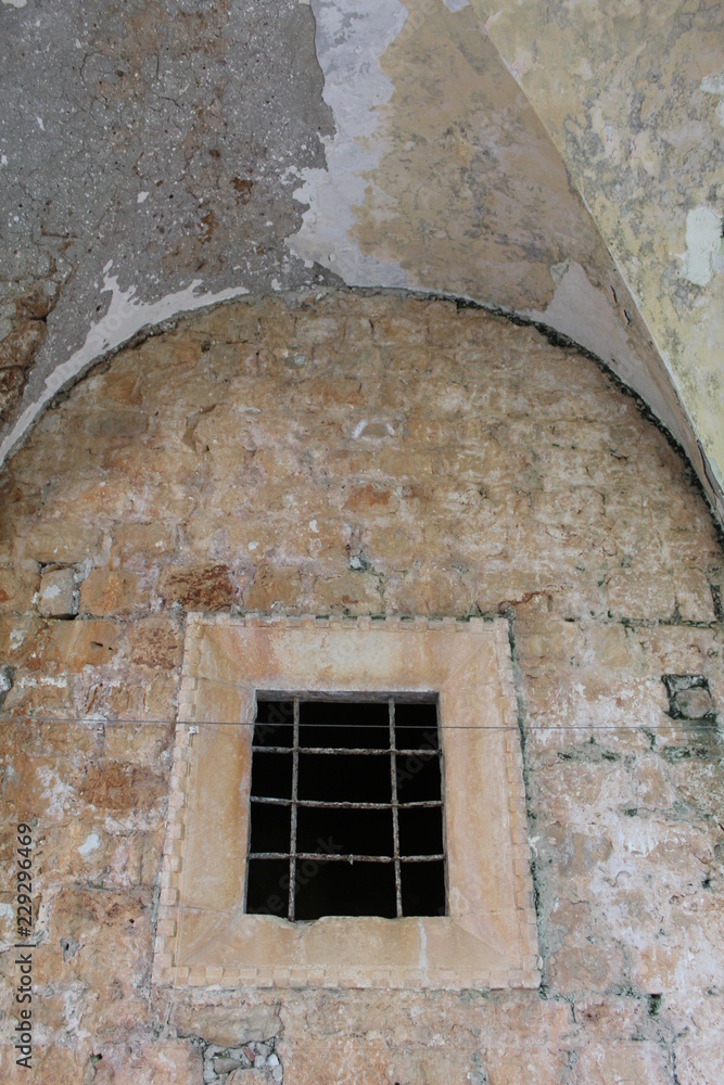 Naklejka premium old barred window in stone wall