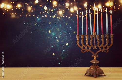 image of jewish holiday Hanukkah background with menorah (traditional candelabra) and candles over glitter shiny background.