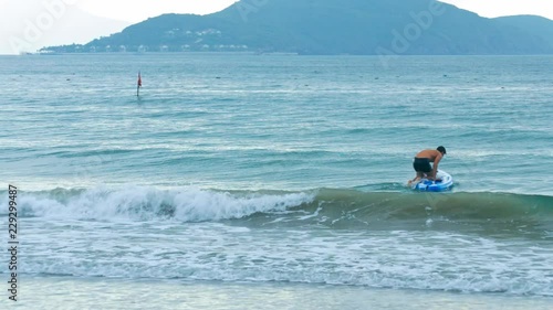 guy goes in ocean gets on paddle board against beach