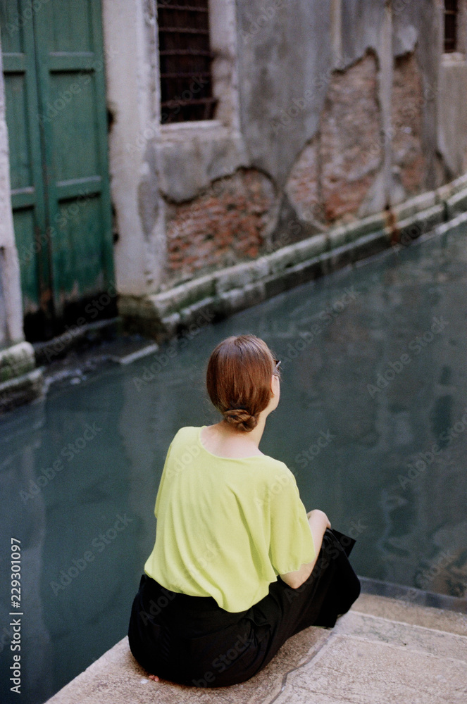 Woman sitting on Venice canal