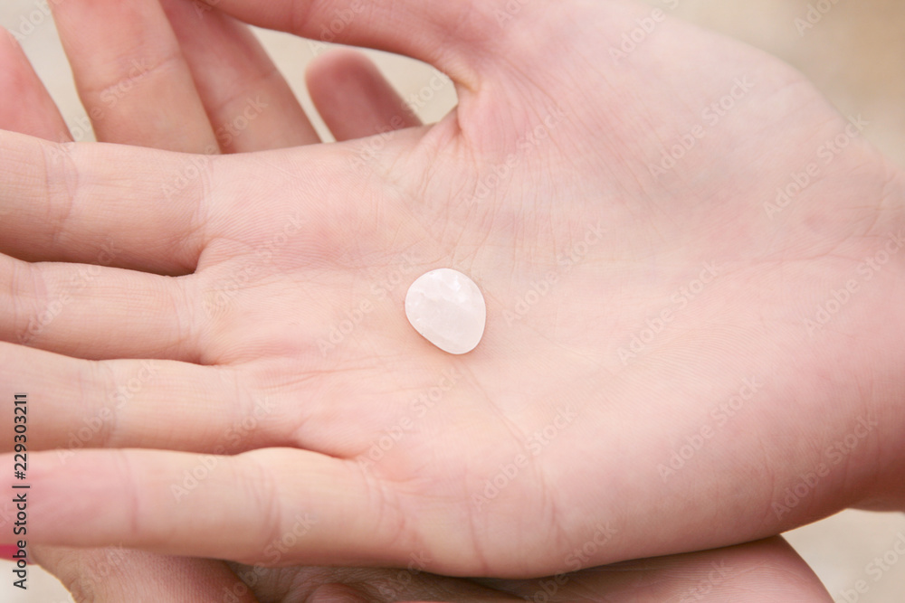 Crossed arms of the girl close up, in the hands of a small white semi transparent moonstone, Crossed arms of the girl close up, in the hands of a small white semi transparent moonstone,