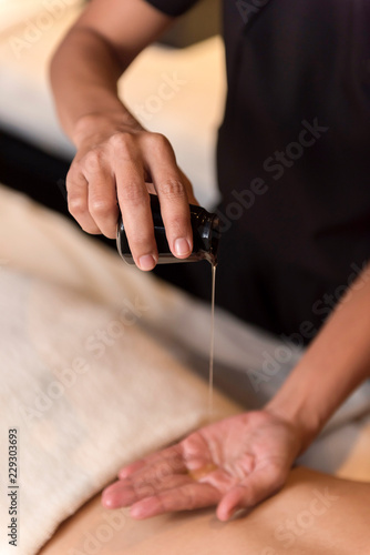 Hand pouring oil for massage in spa