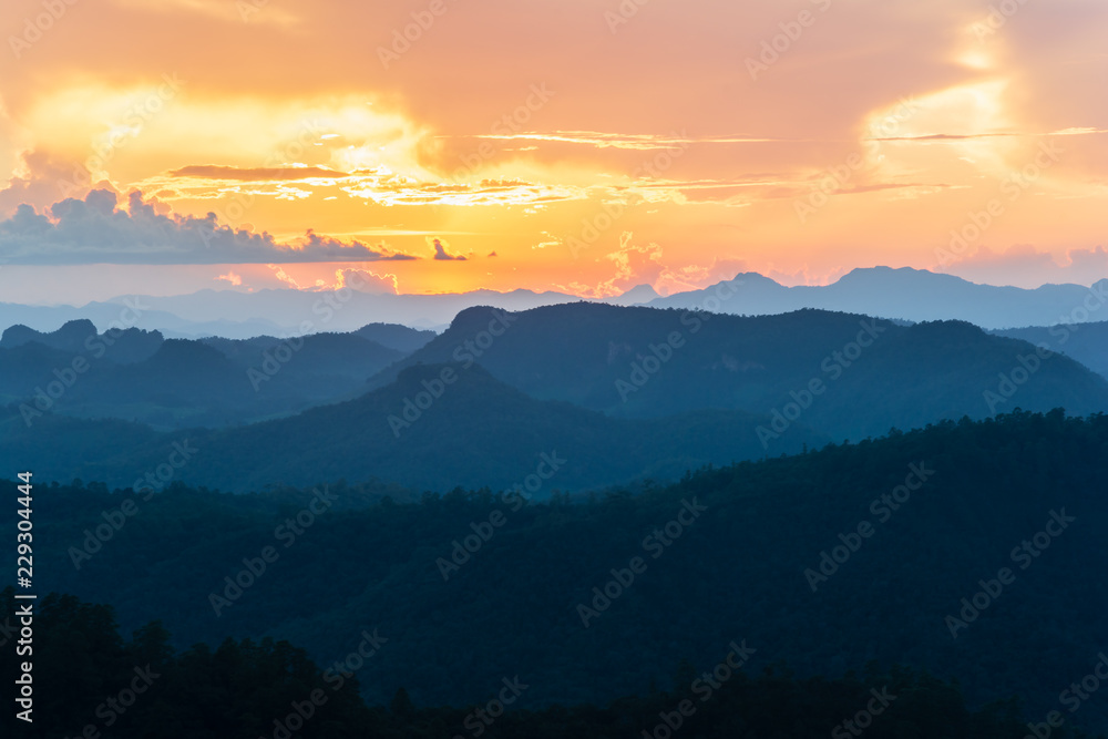 Landscape scene of colorfull sunset sky with mountain range and forest.