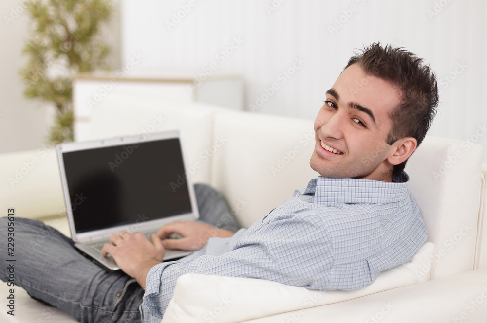 Handsome man is using a laptop, looking at camera and smiling Handsome man is using a laptop, looking at camera and smiling