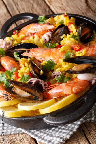 Delicious Spanish paella with seafood and fish close-up in a pan. vertical