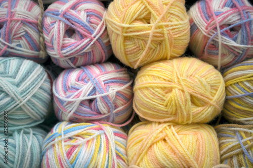 A number of multicolored woolen skeins arranged in rows on a store shelf, yarn texture