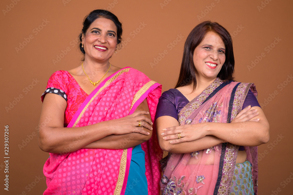 Two happy mature Indian woman smiling with arms crossed