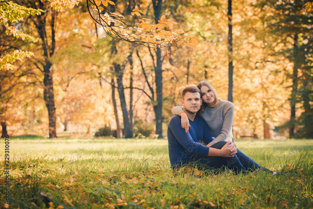 Young beautiful couple is sitting on the meadow Young beautiful couple is sitting on the meadow