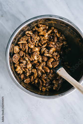 Overhead view of a bowl of mixed nuts, slathered in gingerbread spices, being mixed before baking photo