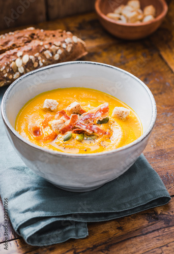 Pumpkin soup with pumpkin seeds and wooden background.