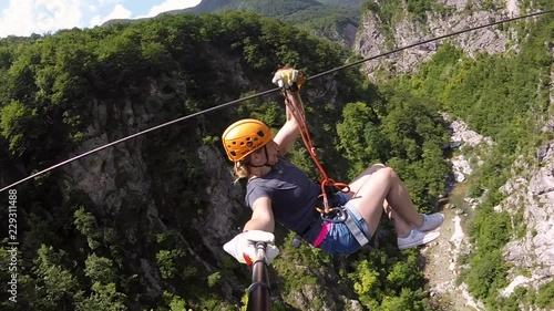 Woman canopying over the forest on zipline in Slovenia.