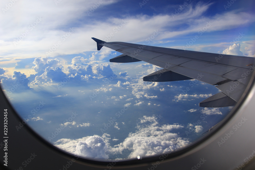 Obraz premium Amazing view from airplane window, Beautiful of Airplane wing with clouds and blue sky on sunset light background