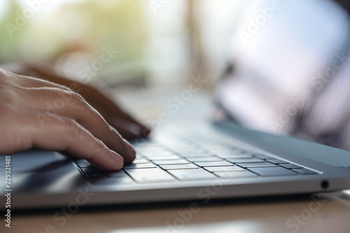 Closeup image of hands using and typing on laptop keyboard on table