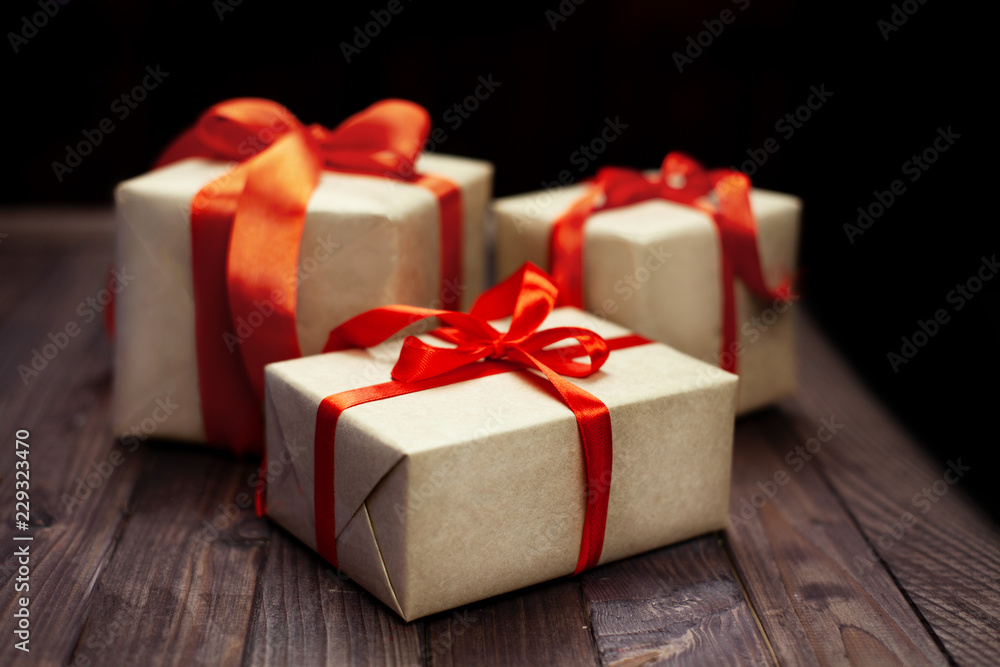 Fototapeta premium Christmas gift boxes and red ribbon on wooden table