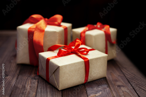 Christmas gift boxes and red ribbon on wooden table © Valentina
