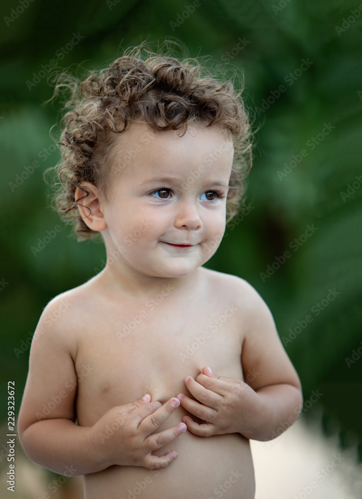 Beautiful baby with curly hair in the garden Beautiful baby with curly hair in the garden