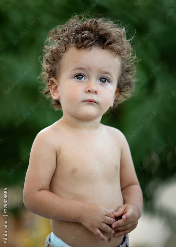 Beautiful baby with curly hair in the garden Beautiful baby with curly hair in the garden