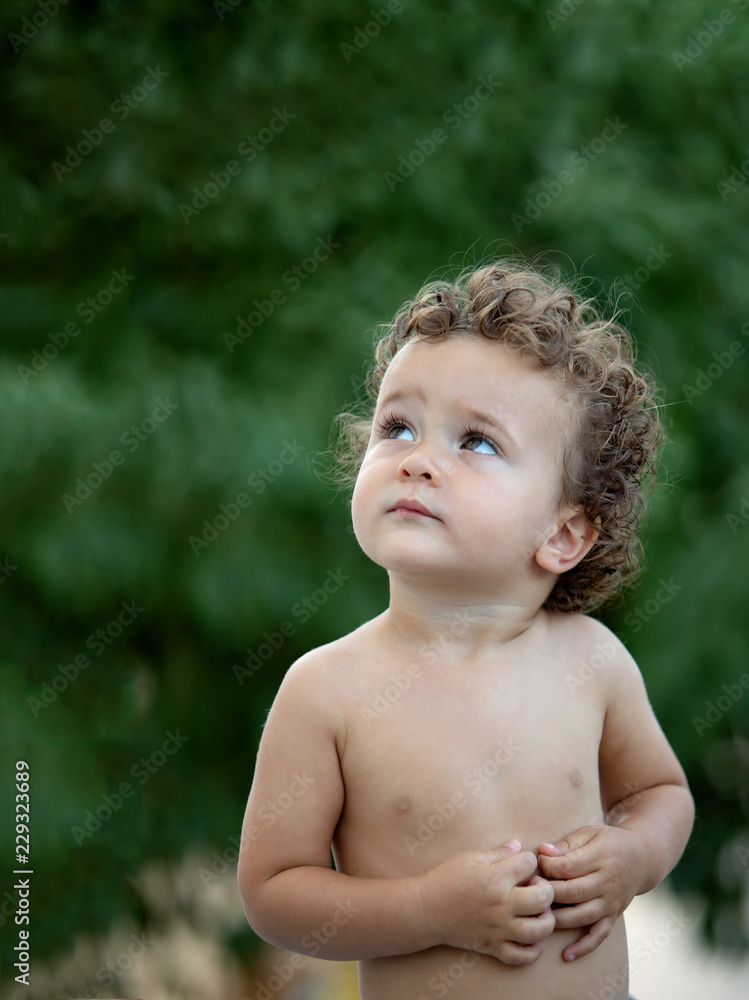 Beautiful baby with curly hair in the garden Beautiful baby with curly hair in the garden