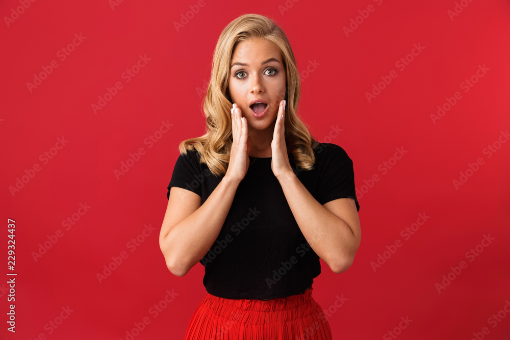Image of excited blonde woman 20s covering open mouth with hands, isolated over red background in studio Image of excited blonde woman 20s covering open mouth with hands, isolated over red background in studio