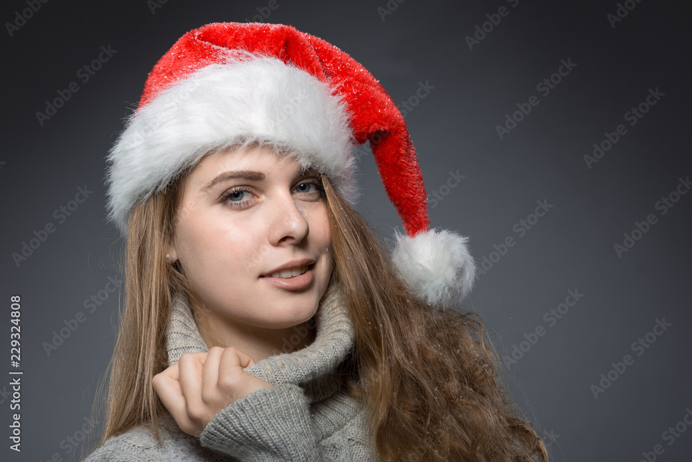 Lächelnde junge Frau im Pulli und Weihnachtsmütze Lächelnde junge Frau im Pulli und Weihnachtsmütze