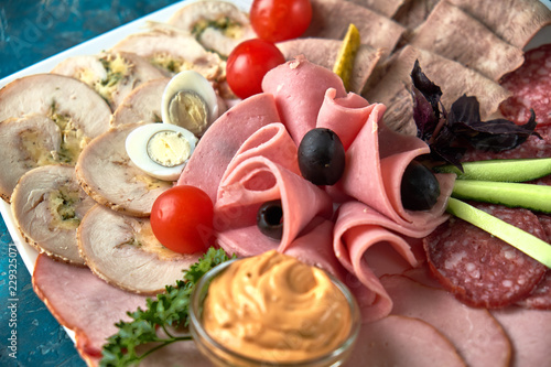 Cold smoked meat plate with prosciutto, salami, bacon, pork chops, cheese and olives on gray stone background.