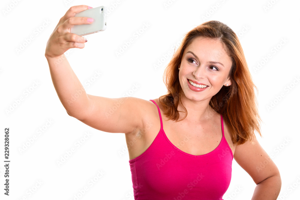 Studio shot of young happy Brazilian woman smiling while taking Studio shot of young happy Brazilian woman smiling while taking